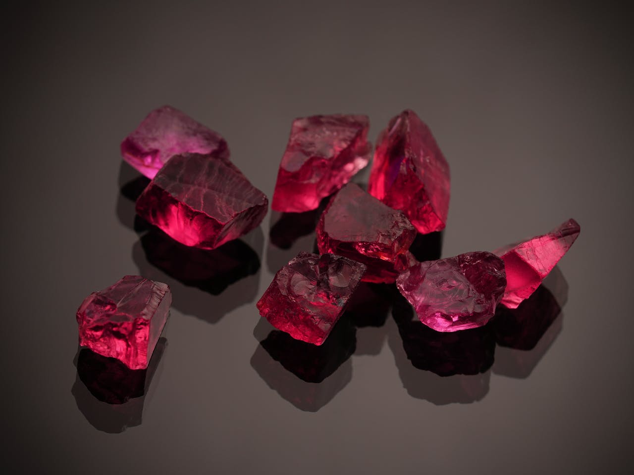 Close-up photo of vibrant red gemstones on a shiny black surface, showcasing brilliance.